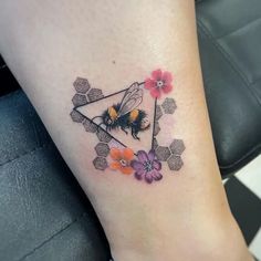 a tattoo on the leg of a woman with flowers and a honeybee in it