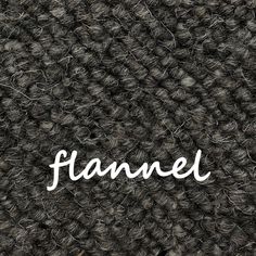 the word flannel written in white ink on a black background with grey yarn