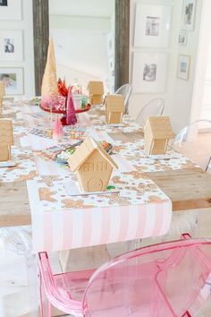 the table is set with gingerbread houses and pink chairs