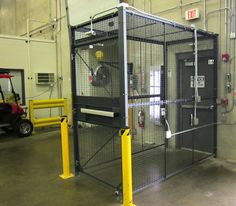 a large metal cage in the middle of a building with yellow poles and barriers around it