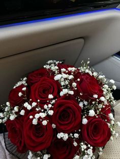 a bouquet of red roses sitting in the back seat of a car with baby's breath