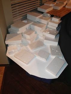 a pile of white boxes sitting on top of a wooden table next to a window