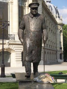 a statue of a man with a hat and cane standing in front of a building