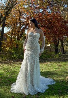 a woman is standing in the grass with her hands on her hips wearing a wedding dress