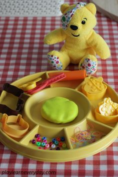 a yellow teddy bear sitting on top of a table next to a tray with food