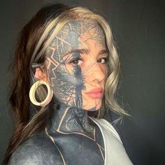 a woman with tattoos on her face and body is posing for a photo in front of a black background