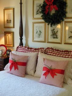 a bed with red and white pillows on top of it next to two framed pictures