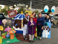 two women and one man are standing in front of a carnival tent with decorations on it