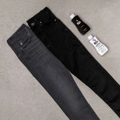 two pairs of black jeans sitting on top of a floor next to a bottle of deodorant