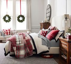 a bedroom decorated for christmas with wreaths on the windowsill and plaid bedding