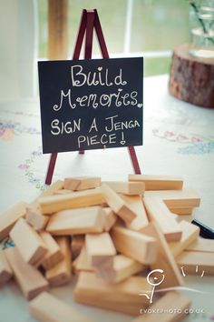 a pile of wooden blocks sitting on top of a table next to a sign that says build memories