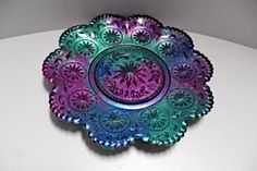 a purple and green glass plate sitting on top of a white table next to a wall