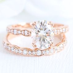 an engagement ring and wedding band set with a round diamond in the center, on top of a white background