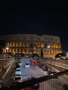 the colossion is lit up at night with cars parked on the street below