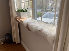 a window sill with a potted plant on it next to a white curtain