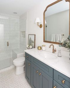 a bathroom with blue cabinets and white tile flooring is pictured in this image, there are two mirrors on the wall above the sink