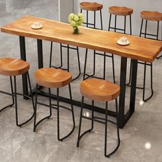 a wooden table with four stools and a vase on the top, in front of it