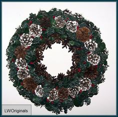 a christmas wreath with pine cones, holly and other evergreen leaves is shown in front of a white background