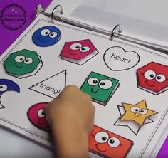 a hand is pointing to an activity book with different shapes and numbers on it,