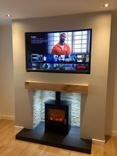 a flat screen tv mounted on the wall above a fireplace with a fire place in front of it