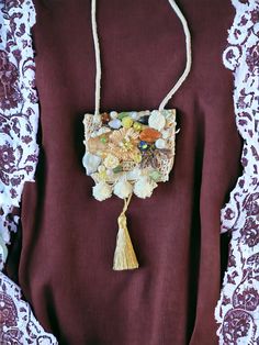 This necklace is a unique art to wear, handmade necklace with an oversize pendant that has been handcrafted in an avant-garde/boho chic style. It is made of beads,lace, fabric on a felt pad with a metal chain. The pendant size is approximately 4.5" x 3.75" and the necklace length is adjustable (18" long when on). This necklace can be worn on many occasions such as parties, weddings, and other special events. It is a unique piece of jewelry that can add a touch of elegance and sophistication to a Bohemian Pendant Necklace With Unique Design, Artisan Necklace With Artistic Pendant Design, Artisan Pendant Necklace With Artistic Design, Handmade Gold Necklace Wearable Art, Unique Necklace With Large Pendant For Festivals, Bohemian Pendant Necklace With Artistic Design, Bohemian Necklace With Large Rectangular Pendant, Multicolor Handmade Necklace Wearable Art, Handmade Artistic Pendant Necklaces