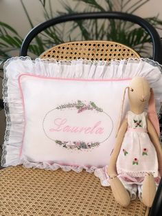 a stuffed animal sitting on top of a chair next to a pillow that says laurella