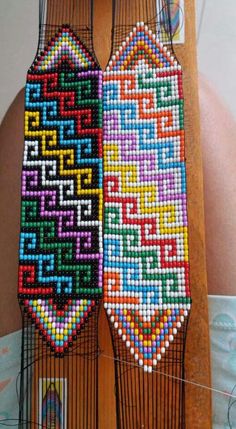 two pieces of beaded art hanging on a wall