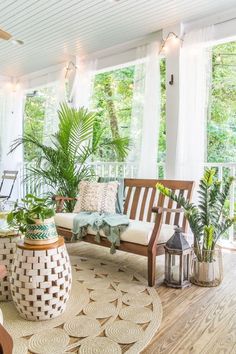 a living room filled with lots of plants and furniture on top of a hard wood floor