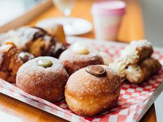 there are many different types of doughnuts on the table with red and white checkered paper