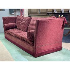 a red couch sitting on top of a carpet covered floor next to a wooden table