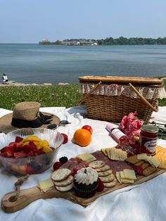 a picnic table with fruit, cheese and crackers on it next to the ocean