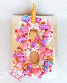 a cake decorated with pink, yellow and blue icing has an unicorn horn on it