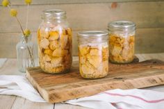 three jars filled with food sitting on top of a wooden board