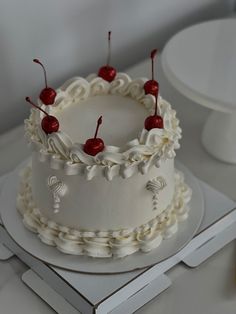 a cake with white icing and cherries on it sitting on top of a table