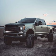 a silver truck parked on top of a dirt road