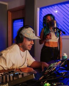 a man wearing headphones sitting in front of a laptop computer next to a woman