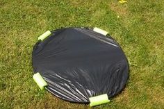 a black tarp sitting on top of a lush green field next to a yellow frisbee