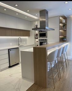 a kitchen with white cabinets and stainless steel appliances in the center, along with bar stools