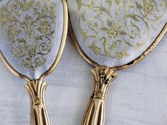 two gold colored mirrors with ornate designs on them