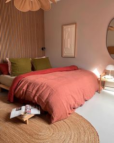 a bed sitting in a bedroom next to a mirror and table with two lamps on it