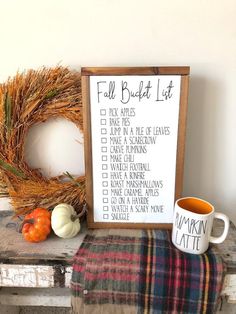 a fall bucket list next to a coffee mug on a table with pumpkins and a wreath