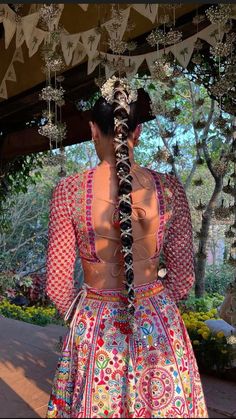 a woman in a colorful dress standing under a canopy with beads hanging from it's sides