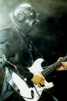 a man in a gas mask playing an electric guitar