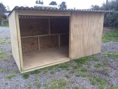 a wooden storage shed sitting on top of a gravel field