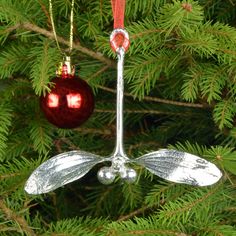 an ornament hanging from a christmas tree with two red ornaments on it's side