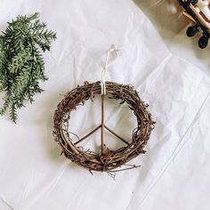 a twig wreath is hanging on a white piece of paper next to a plant