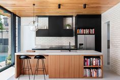 a kitchen with two stools next to an island and bookshelves on the wall