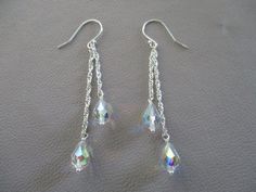 These sparkly earrings have 9x6mm clear Austrian crystal teardrops with an AB finish wire wrapped onto different lengths of sparkly sterling silver Singapore rope chain, hanging from sterling silver ear wires. The length is 2" from the ear wire loop. The AB stands for aurora borealis, a colorful rainbow finish. Silver Crystal Dangle Teardrop Earrings, Silver Crystal Teardrop Dangle Earrings, Sterling Silver Long Drop Teardrop Earrings For Party, Silver Sparkling Dangle Teardrop Earrings, Sparkling Silver Dangle Teardrop Earrings, Teardrop Crystal Earrings With Ear Wire, Teardrop Wire Wrapped Crystal Earrings For Party, Silver Hypoallergenic Teardrop Crystal Earrings, Sterling Silver Teardrop Crystal Earrings With Ear Wire