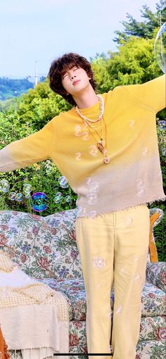 a woman standing on top of a couch next to a flower covered bed with her arms outstretched