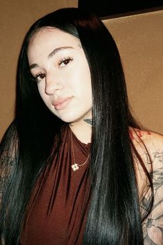 a woman with long black hair and tattoos on her arm, posing for the camera